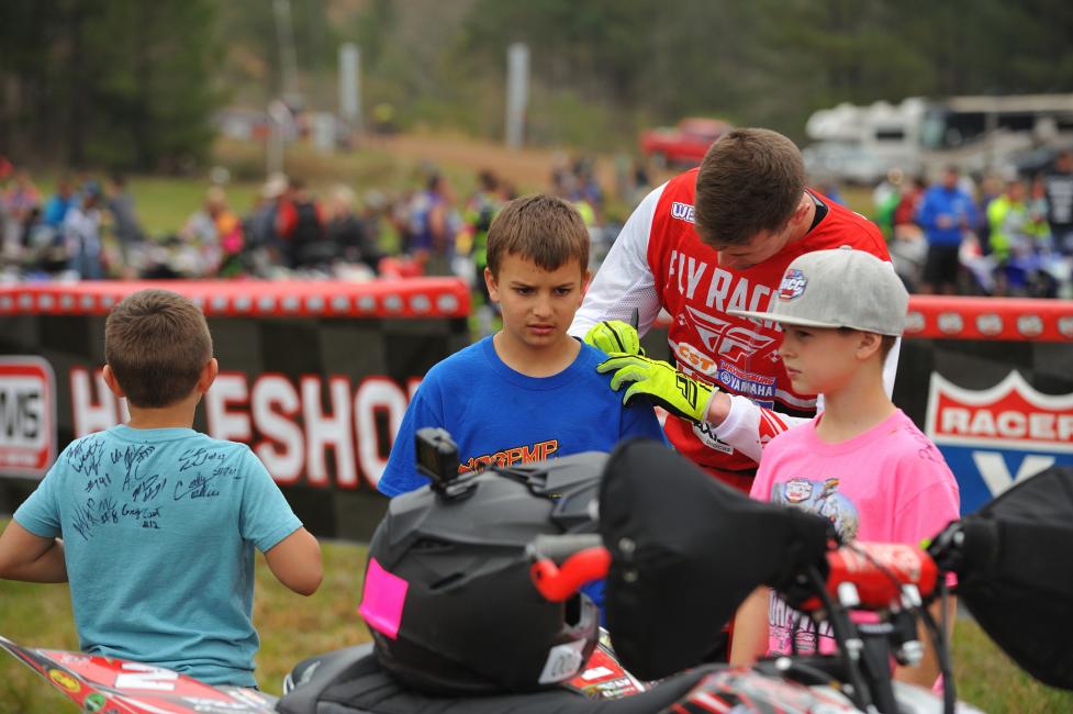 Making time to sign autographs for his fans before the start of his race.